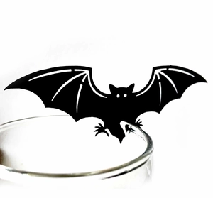 Close-up of a black bat cup card ornament on a glass rim for Halloween party decor