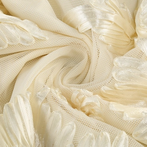 Close-up of elegant 3D floral appliques and sheer mesh texture on a beige dress