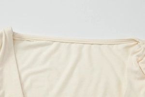Dettaglio dello scollo a V e delle cuciture sul tessuto beige del crop top arricciato