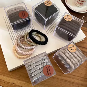 Five-piece set of satin scrunchies in earth tones displayed in a clear gift box