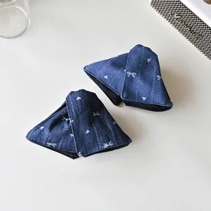 Vue détaillée des pinces à cheveux en denim avec broderie papillon blanc sur tissu bleu