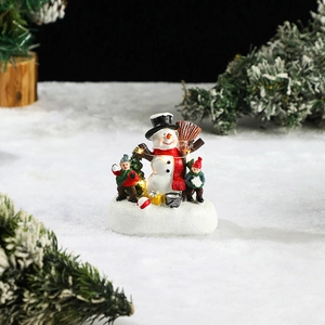 Detail of glowing Christmas snowman figurine with children on a snowy lighted base