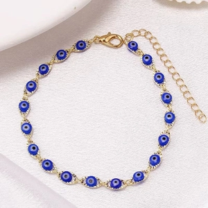 Detailed close-up of golden evil eye anklet with blue beads and adjustable lobster clasp