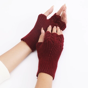 Detail of dark red knit fingerless gloves showing intricate fish scale texture on wrist