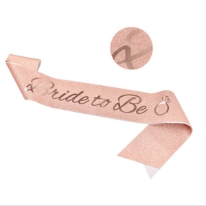 Macro shot of rose gold glitter sash texture with Bride to Be script and ring icon