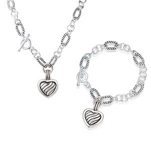 Detail of silver heart charm with wavy texture and T-bar clasp on a twisted link chain