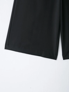 Détail du pantalon taille haute montrant l'ourlet à double couture et le tissu noir lisse