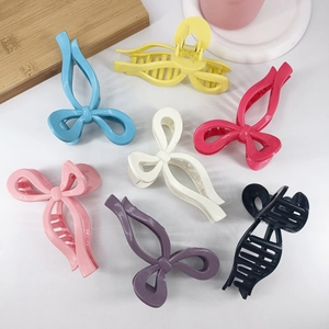 Detailed top view of seven colorful bow-shaped plastic hair claws in glossy finish