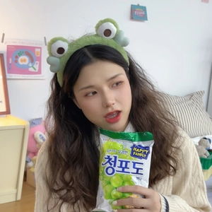 Close-up of green plush frog headband with big eyes worn for daily face washing