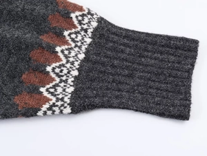 Close-up of dark grey knitted sweater featuring geometric patterns and ribbed cuffs