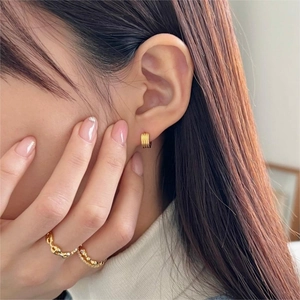 Detail showing gold striped hoop earrings and stacked rings on a model hand