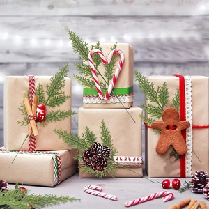 Christmas gift boxes with pine needles, candy canes and festive ornaments on wood