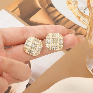 Elegant gold square stud earrings with mini pearls and crystals on a model's hand