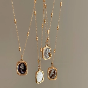 Detail of four vintage gold rose relief pendants with embossed oval design on bead chains