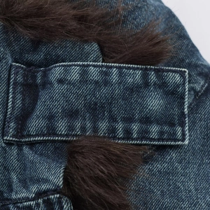 Detail shot of heavy blue denim fabric with luxury brown faux fur trim and stitching