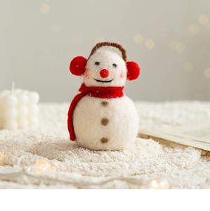 Handmade wool felt snowman decoration with red scarf on a white plush rug background