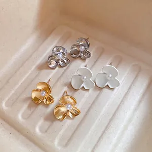 Three pairs of floral pearl stud earrings in gold silver and matte white finish