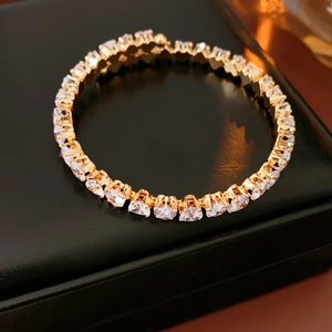 Close-up of a gold-plated tennis bracelet with shimmering cubic zirconia on black leather