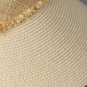 Detailed close-up of woven straw texture and stylish fringe on a summer sun visor hat