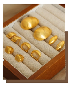Detailed set of five pairs of matte gold geometric earrings in a wooden jewelry box
