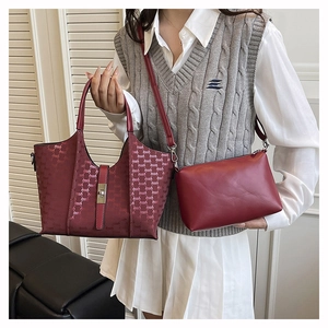Detail of red tote bag set with monogram embossing and matching clutch on a model