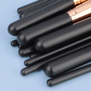 Detailed close-up of matte black makeup brushes with rose gold metal ferrules and soft bristles