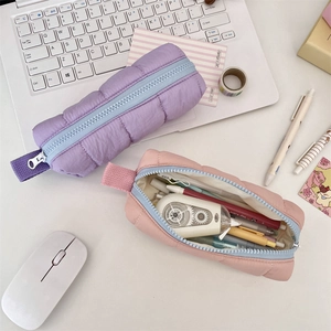 Macro detail of quilted puffy pencil cases in pastel pink and purple on a desk