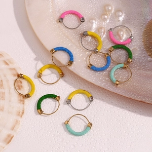 Macro shot of colorful enamel 18K gold plated hoop earrings on seashell with water drops