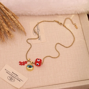 Detailed shot of golden necklace with evil eye pendants and red coral on beige fabric