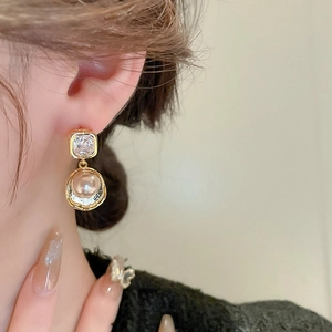 Close-up of vintage zircon and champagne pearl drop earrings on model's ear detail
