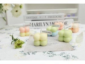Artistic arrangement of macaron-colored bubble candles with vintage books and flowers