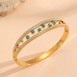 Bracelet jonc doré avec pierres turquoise et zircons sur fond minéral chaleureux