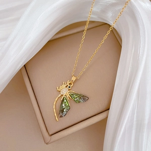 Close-up of golden dragonfly necklace with green enamel wings and sparkling crystals