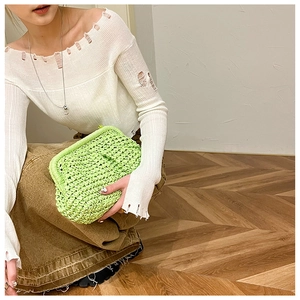 Close-up of a neon green woven straw handbag featuring a textured knot strap detail