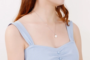 Gros plan d'un collier en acier titane argenté avec une perle blanche porté par un mannequin