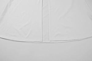 Macro di un abito bianco in rete con cuciture precise e spacco centrale sulla gonna