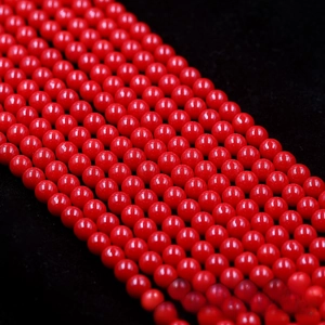 Macro shot of polished vibrant red round beads neatly arranged on black velvet background