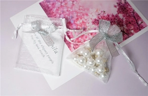 Close-up of white organza drawstring pouch with silver bow and pearl accessory
