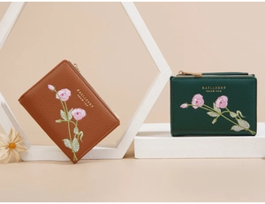 Detail of short tri-fold wallets with floral embroidery and gold brand logo