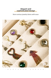 Macro shot of warm beige velvet jewelry tray compartments with brooch and earrings