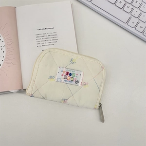 Close-up of quilted cream wallet with colorful stitching and metal zipper detail