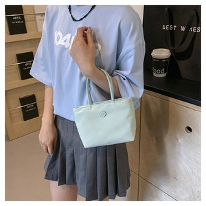 Vue détaillée d'un sac seau en nylon bleu clair avec logo rond sur un mannequin décontracté