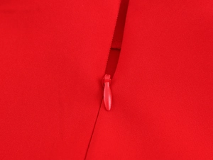 Détail de la fermeture éclair invisible et du tissu rouge texturé de l'ensemble jupe