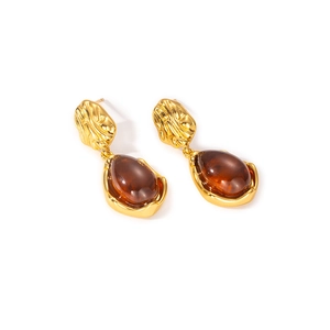 Detailed shot of vintage amber teardrop earrings with textured gold titanium steel metal