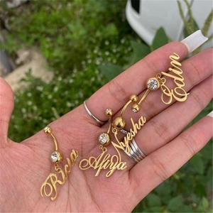 Detailed view of four golden belly rings with clear crystals and custom name pendants