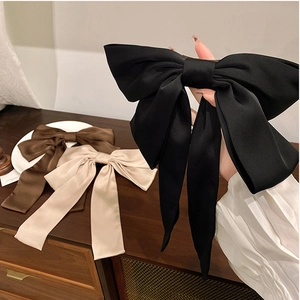 Détail de grandes barrettes à nœud en satin en noir, marron et beige classique