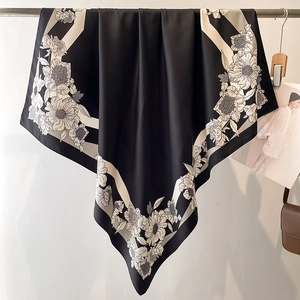 Detail of a large black and white floral print silk scarf elegantly draped on a rail