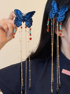 Détail d'épingle à cheveux papillon brodée bleue avec de longs pompons dorés et perles
