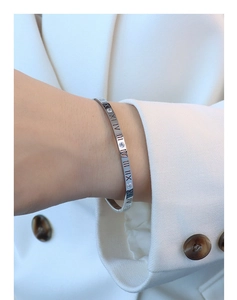 Detail of silver Roman numeral bangle with inset crystals on a model's wrist