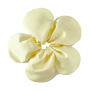 Detail of soft pale yellow satin oversized flower scrunchie with smooth silk texture